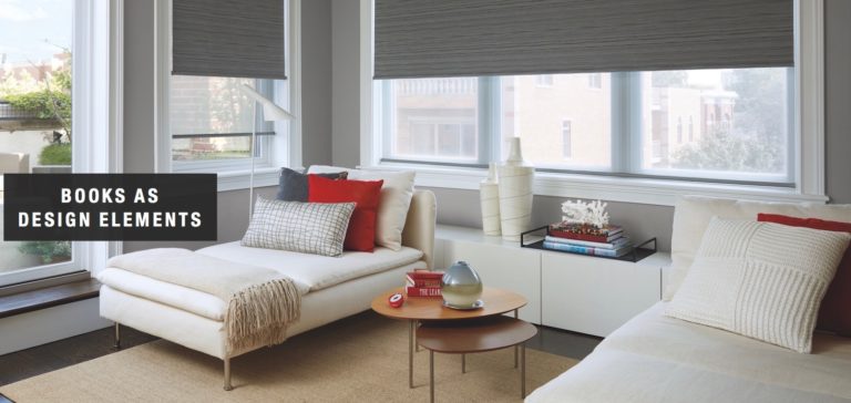 Books stacked on a table become a base for a decorative object. Shown with Designer Roller Shades.